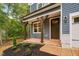 Inviting front porch featuring wood columns, landscaping, a dark front door and blue siding at 125 Oswego Dr, Louisburg, NC 27549