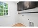Bright laundry room with white shiplap walls, black cabinets, and a view from the window at 125 Oswego Dr, Louisburg, NC 27549
