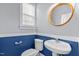 Cozy bathroom features a pedestal sink, framed round mirror, and blue wainscoting at 130 Virginia Water Dr, Rolesville, NC 27571