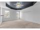 Spacious carpeted bedroom featuring a tray ceiling, ceiling fan, and two large windows at 130 Virginia Water Dr, Rolesville, NC 27571