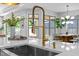 Close up of a kitchen island sink with a gold faucet, quartz countertops, and view of the dining area at 248 Speight Branch Rd, Cary, NC 27518