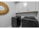 Modern laundry room featuring black washer and dryer with white cabinets at 248 Speight Branch Rd, Cary, NC 27518