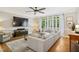 Bright living room featuring hardwood floors, large windows, a ceiling fan, and a sectional sofa at 4001 Falls River Ave, Raleigh, NC 27614