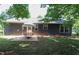 Exterior rear of house with patio table and chairs surrounded by green grass and trees at 420 E Grandview Ave, Liberty, NC 27298