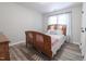 Bright bedroom features wood-look floors, a wood frame bed, and a window letting in natural light at 420 E Grandview Ave, Liberty, NC 27298
