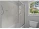 Bright bathroom featuring a tiled shower behind a glass enclosure, a window, and a toilet at 5344 Mill Dam Rd, Wake Forest, NC 27587