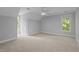 An empty bedroom with a carpeted floor and two large windows that let in plenty of sunlight at 5344 Mill Dam Rd, Wake Forest, NC 27587