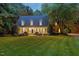 Charming two-story home with a lush green lawn, manicured landscaping, and mature trees at dusk at 5344 Mill Dam Rd, Wake Forest, NC 27587