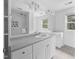 Bright bathroom with white vanity, mirror reflecting the shower, and neutral-toned tile flooring at 5601 Buffaloe Rd, Raleigh, NC 27616