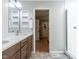 Bathroom with double sink vanity with wood cabinets, a glass shower stall, and view to a bedroom at 5809 Kimbal St, Raleigh, NC 27606