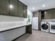 This laundry room features a countertop with hanging cabinets and new front-load washer and dryer at 5809 Kimbal St, Raleigh, NC 27606
