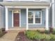 Inviting front porch with a red front door, white columns, and beautiful plantings at 6536 Perry Creek Rd, Raleigh, NC 27616