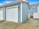 Detached garage with a white door, blue siding, and exterior lighting at 6536 Perry Creek Rd, Raleigh, NC 27616