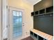 A mudroom features a built-in bench with storage and coat hooks near a door with window blinds at 6536 Perry Creek Rd, Raleigh, NC 27616