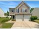 Two-story home with a two-car garage, tan siding, blue shutters, and manicured lawn on a clear day at 735 Sycamore Springs Dr, Fuquay Varina, NC 27526