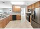 Well-lit kitchen with stainless steel appliances, ample wooden cabinetry, and tiled flooring at 735 Sycamore Springs Dr, Fuquay Varina, NC 27526