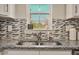 This features the kitchen sink, window, granite countertops and the decorative backsplash at 784 Crawford Rd, Coats, NC 27521