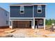 Two story home exterior with blue siding, garage, and construction materials surrounding the property at 800 Ottawa Dr, Garner, NC 27529