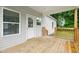 Inviting back porch featuring wood flooring and railings with views of the lush green backyard and natural light at 807 S Mebane St., Burlington, NC 27215