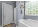 Bright bathroom featuring a tub with a block glass window and a white door to the shower at 101 Hazel Ln Ln, Broadway, NC 27505