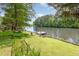 Backyard leading to a serene lake, featuring lush greenery and a private pier with a ladder at 1033 Sagamore Dr, Louisburg, NC 27549