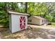 A small shed with a red and white door sits on the property alongside the house with lakeside access at 1033 Sagamore Dr, Louisburg, NC 27549