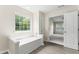 Bathroom featuring a tub with tile surround and a large window with bright natural light at 107 Woolard Way, Apex, NC 27502