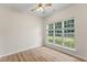 Cozy bedroom with hardwood floors, a ceiling fan, and a large window overlooking the lush yard at 107 Woolard Way, Apex, NC 27502