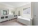 Bright main bathroom featuring dual sinks, a soaking tub, and a large window at 107 Woolard Way, Apex, NC 27502