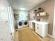 Bright laundry room offers white cabinets, counter space, open shelving, and modern washer and dryer units at 11609 Us 401, Fuquay Varina, NC 27526