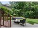 A serene back patio is furnished with a round table and chairs, overlooking a lush green lawn and wooded area at 118 Killingsworth Dr, Cary, NC 27518