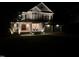 Inviting two-story home featuring stone accents, a covered porch with seating, and an attached two-car garage at night at 118 Killingsworth Dr, Cary, NC 27518