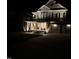 Inviting two-story home featuring stone accents, a covered porch with seating, and an attached two-car garage at night at 118 Killingsworth Dr, Cary, NC 27518