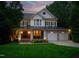 Elegant two-story home at twilight, showcasing warm lighting on the porch and landscape at 118 Killingsworth Dr, Cary, NC 27518