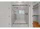 A glass enclosed shower with black hardware and marble threshold and an adjacent walk-in closet with wood floor at 120 Firefly Ln, Louisburg, NC 27549