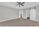 Carpeted bedroom leading to the ensuite bathroom, featuring a gray color scheme, ceiling fan, and natural light at 121 Nate Ct, Wake Forest, NC 27587