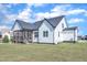 The rear exterior of a modern white home with a screened porch and gray roof stands on a well-maintained lawn at 121 Nate Ct, Wake Forest, NC 27587