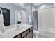 Bright bathroom with a black door, features a modern vanity, a toilet and a shower-tub combo with white subway tiles at 1716 Aberdour Dr, Apex, NC 27502