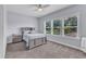 This bright bedroom has carpet floors, a gray bed set and a window with view to green trees at 1716 Aberdour Dr, Apex, NC 27502