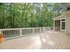 Wide back deck with white railings offers serene views of the lush greenery and mature trees at 286 Harrison Pond Dr, Pittsboro, NC 27312