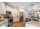 Well-lit kitchen featuring stainless steel appliances, granite countertops, and hardwood floors at 286 Harrison Pond Dr, Pittsboro, NC 27312