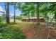 Spacious backyard with mature trees, a playground, and a brick home with a deck at 2968 Tram Rd, Fuquay Varina, NC 27526