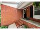 Close-up of a welcoming red brick front porch with black door and stylish plants at 2968 Tram Rd, Fuquay Varina, NC 27526