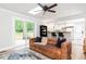 Bright living room features a brown leather sofa, wood floors, and a sliding glass door to the backyard deck at 2968 Tram Rd, Fuquay Varina, NC 27526