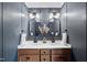 Stylish bathroom with double sink vanity, oval mirrors, modern lighting and blue-grey walls at 3705 Highland Creek Dr, Apex, NC 27539