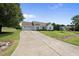 View of the exterior showcasing a lengthy driveway, landscaped yard, and a well-maintained white house at 3705 Highland Creek Dr, Apex, NC 27539