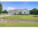 Charming white home with a two-car garage, well-maintained lawn, and a lovely creek running through the front yard at 3705 Highland Creek Dr, Apex, NC 27539