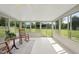 Bright sunroom with white floors, ceiling fan, rocking chairs, and large windows offering views of the landscaped backyard at 3705 Highland Creek Dr, Apex, NC 27539