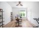 Modern office with light wood flooring, fan, large windows, and black shelving for storage and decor at 386 Monteith Dr, Chapel Hill, NC 27516