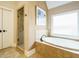 Bright bathroom with soaking tub, glass shower, and warm, neutral tile work at 410 Mountain Laurel, Chapel Hill, NC 27517